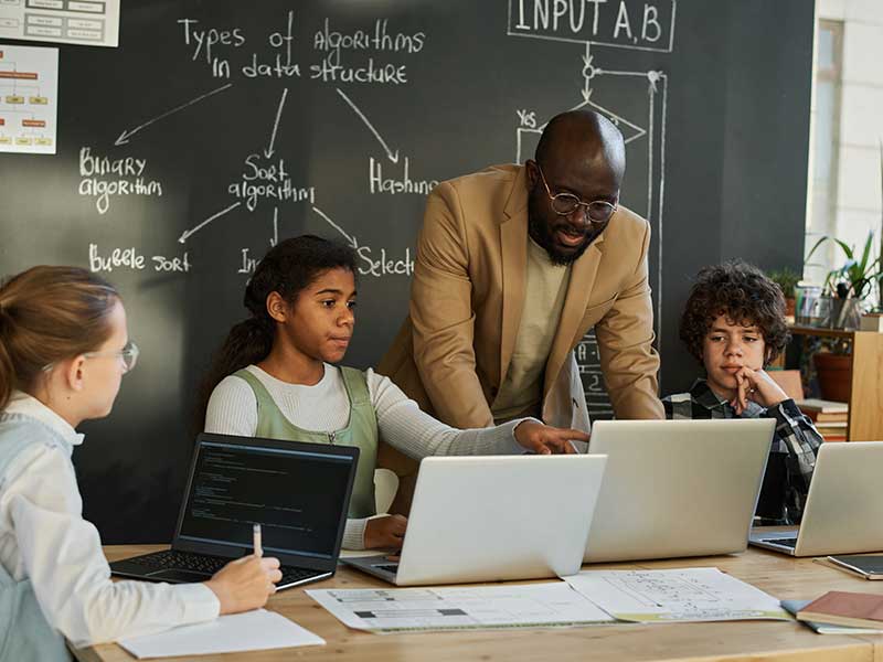 Teacher working with students on their laptops