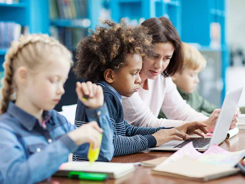 Teaching working on a laptop with a student