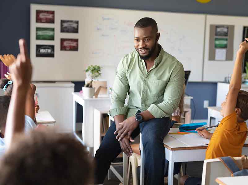 Smiling teacher looking at a classroom of students participating in class
