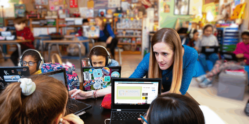 Teacher working with a group of students on their laptops