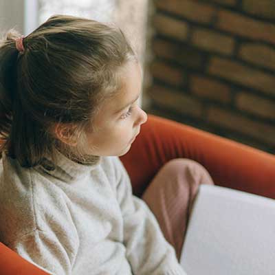 Young student with a book on her lap, staring into the distance