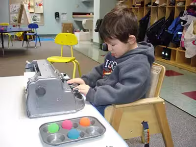 A young elementary student using a Perkins Brailler.