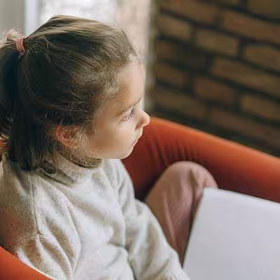 Young student with a book on her lap, staring into the distance